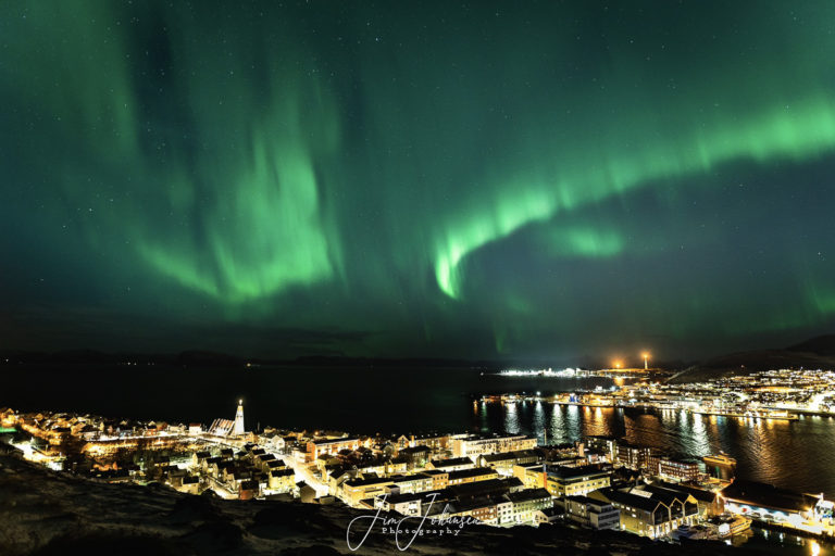 Nordlys sett fra fjellet Salen, kirketårnet midt i bildet og Sørøya i det fjerne på andre sida © Jim Johansen