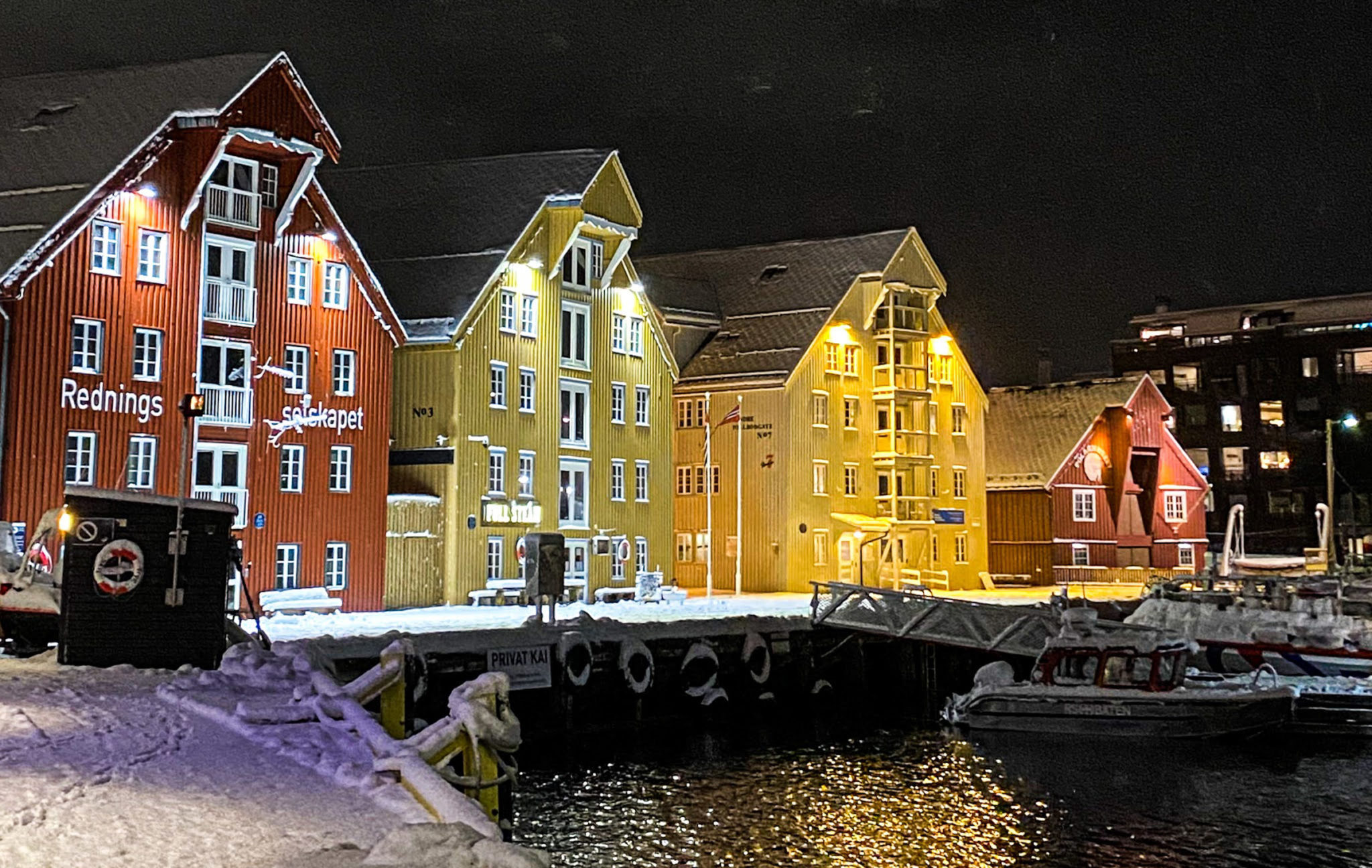 Bryggerekka en vinterkveld. De tre store bryggene er bygd opp etter brann i 1903, mens den lille er Polarmuseet fra 1830-tallet © Knut Hansvold