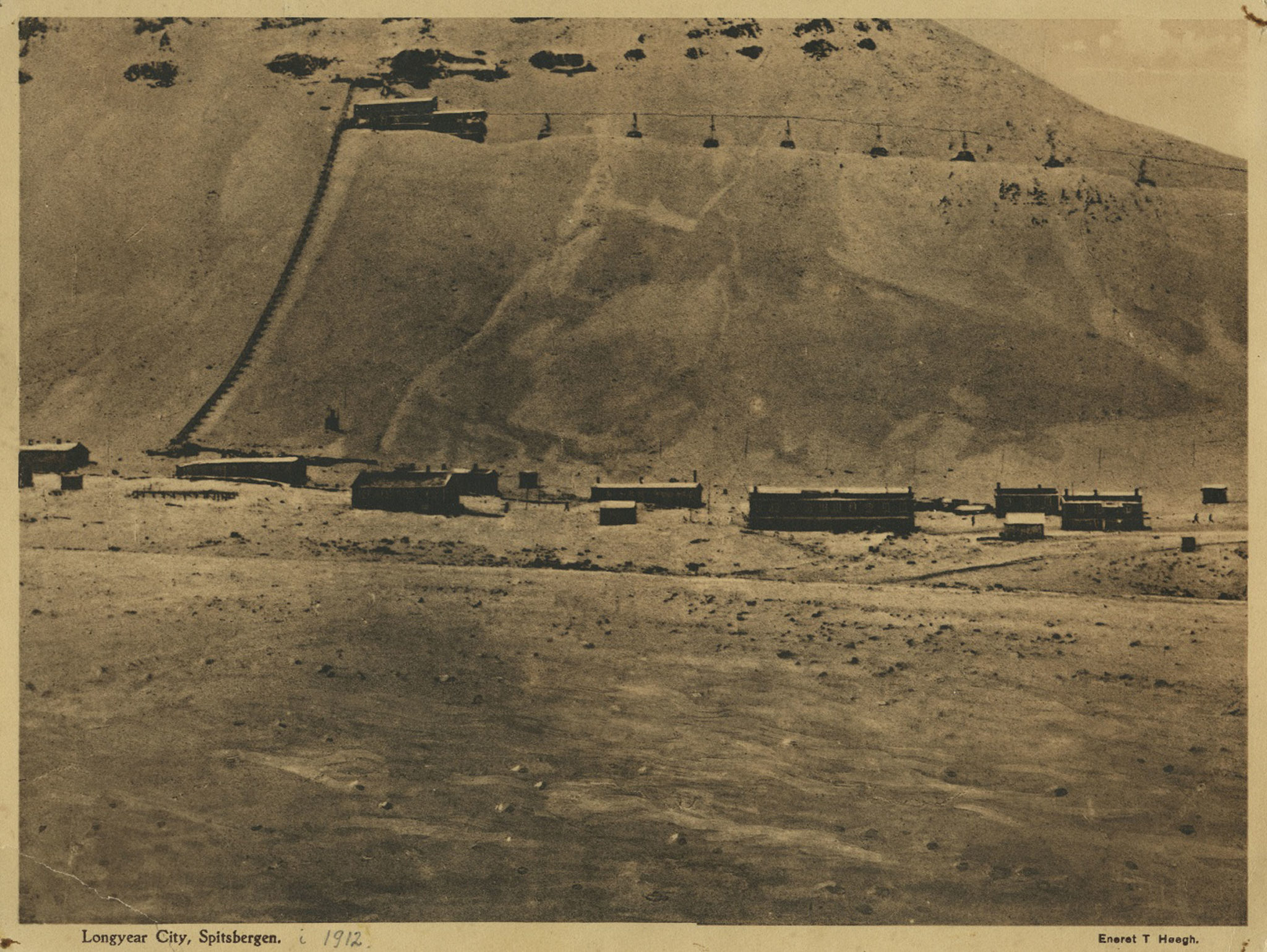 Gruve 1a i gamle Longyearbyen/Longyearbyen City. Anslått tidsperiode: 1925 – 1935. Du kan framdeles se gruven oppe i fjellsiden sammen med taubanebukkene. Om du vil se nærmere på gjenstander fra gruvedrift kan du for eksempel gå hit: https://digitaltmuseum.no/021098865820/sveagruva. Fotograf er ukjent. © Svalbard museum
