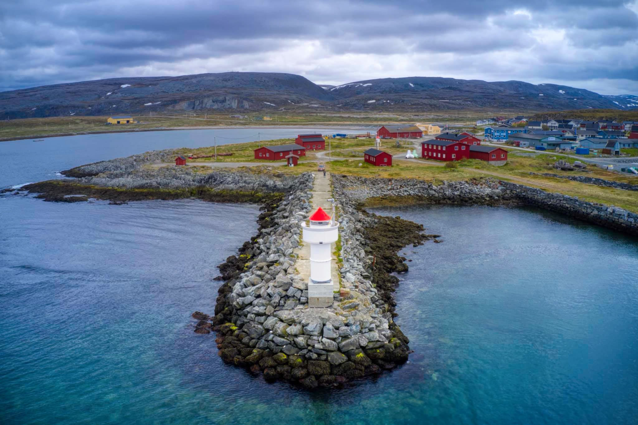 Berlevåg med de røde bygningene som inngår i Havnemuseet. Inngangen er det den hvite og grønne tetrapoden © Havnemuseet i Berlevåg